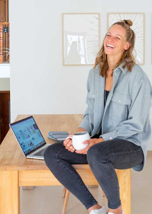 Portrait von Katharina Jöbstl sitzend am Tisch mit Tasse in der Hand MAVI Concepts - Designstudio by Katharina | Brand Design | Webdesign | Grafikdesign